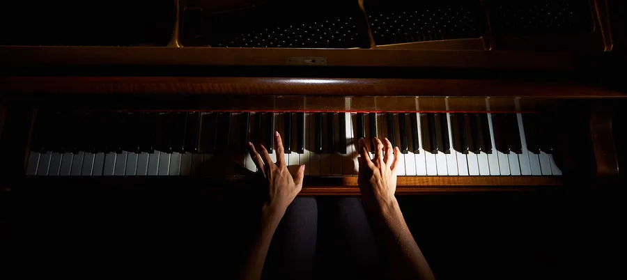Hands playing the piano, viewed from above
